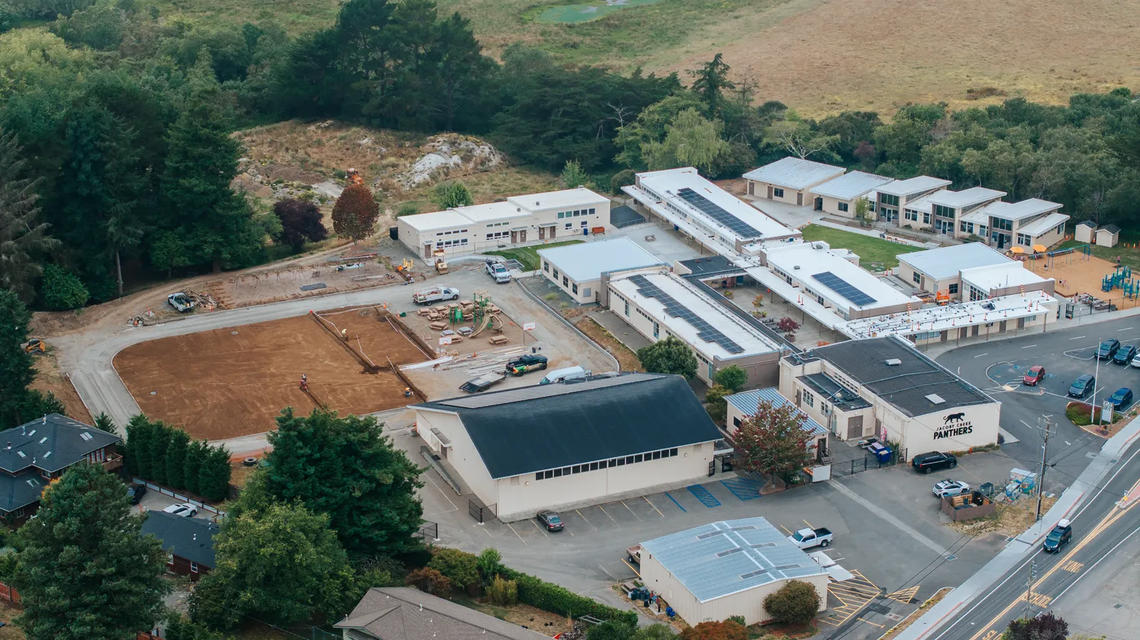 School campus with rooftop solar and field construction from drone elevation