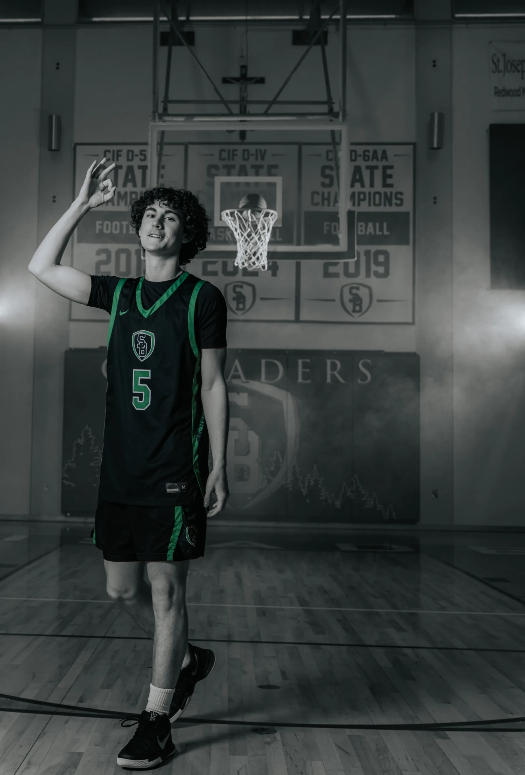 Black-and-white flash portrait, player 5 flipping the ball toward the rim